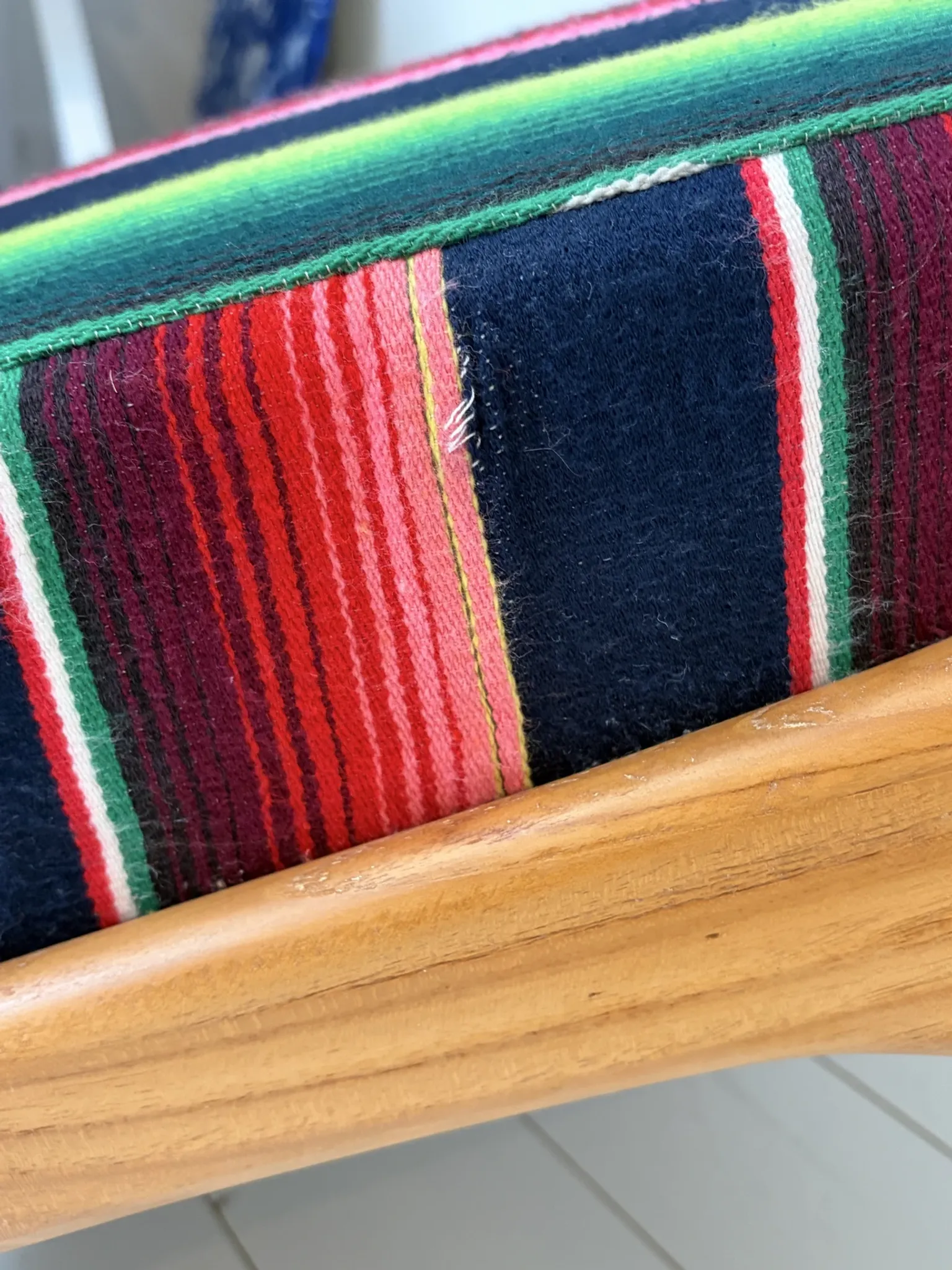 Scandinavian-style armchair in curved wood and colourful striped fabric.