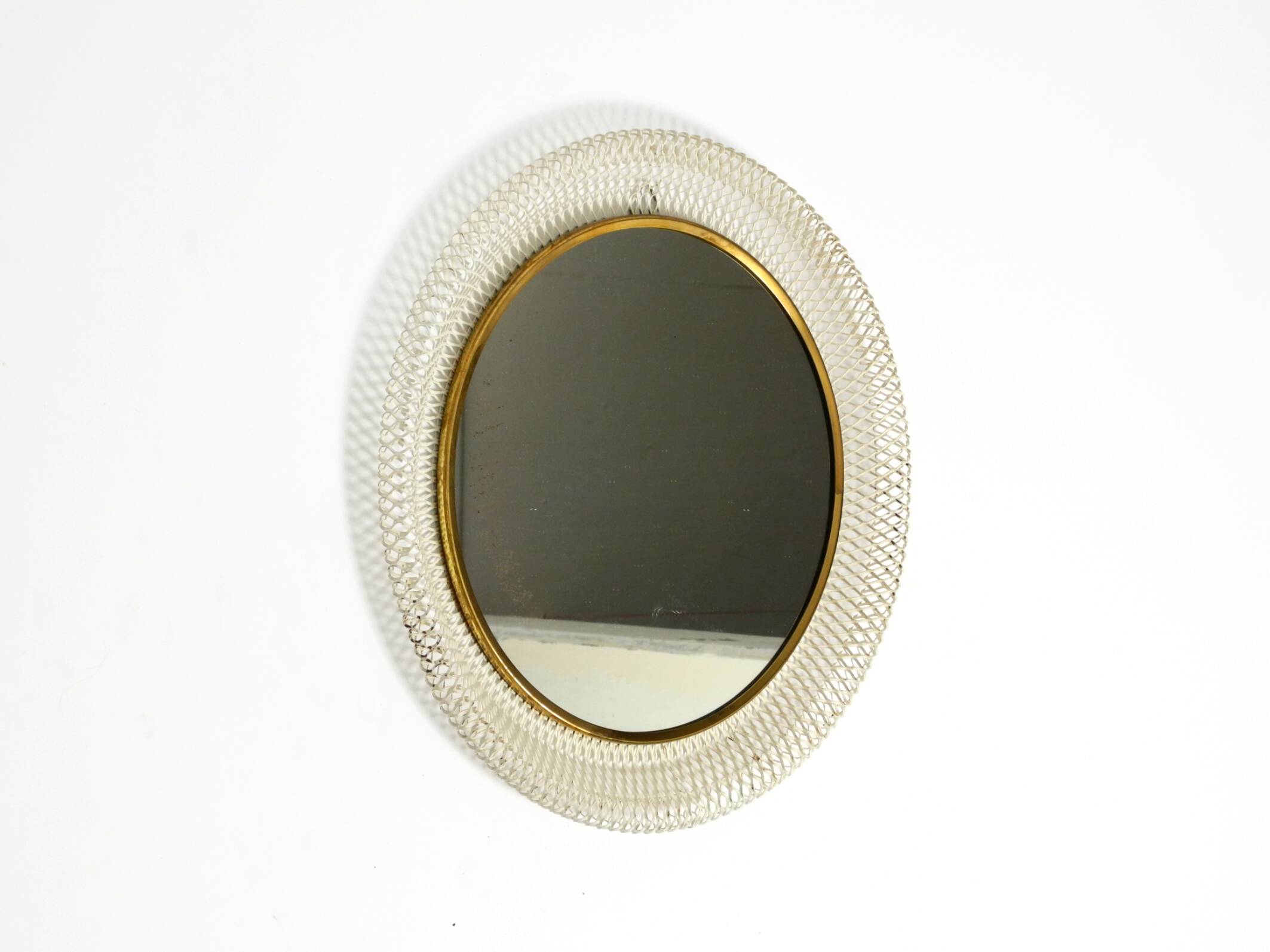 Mid Century Modern round wall mirror with a white expanded metal frame