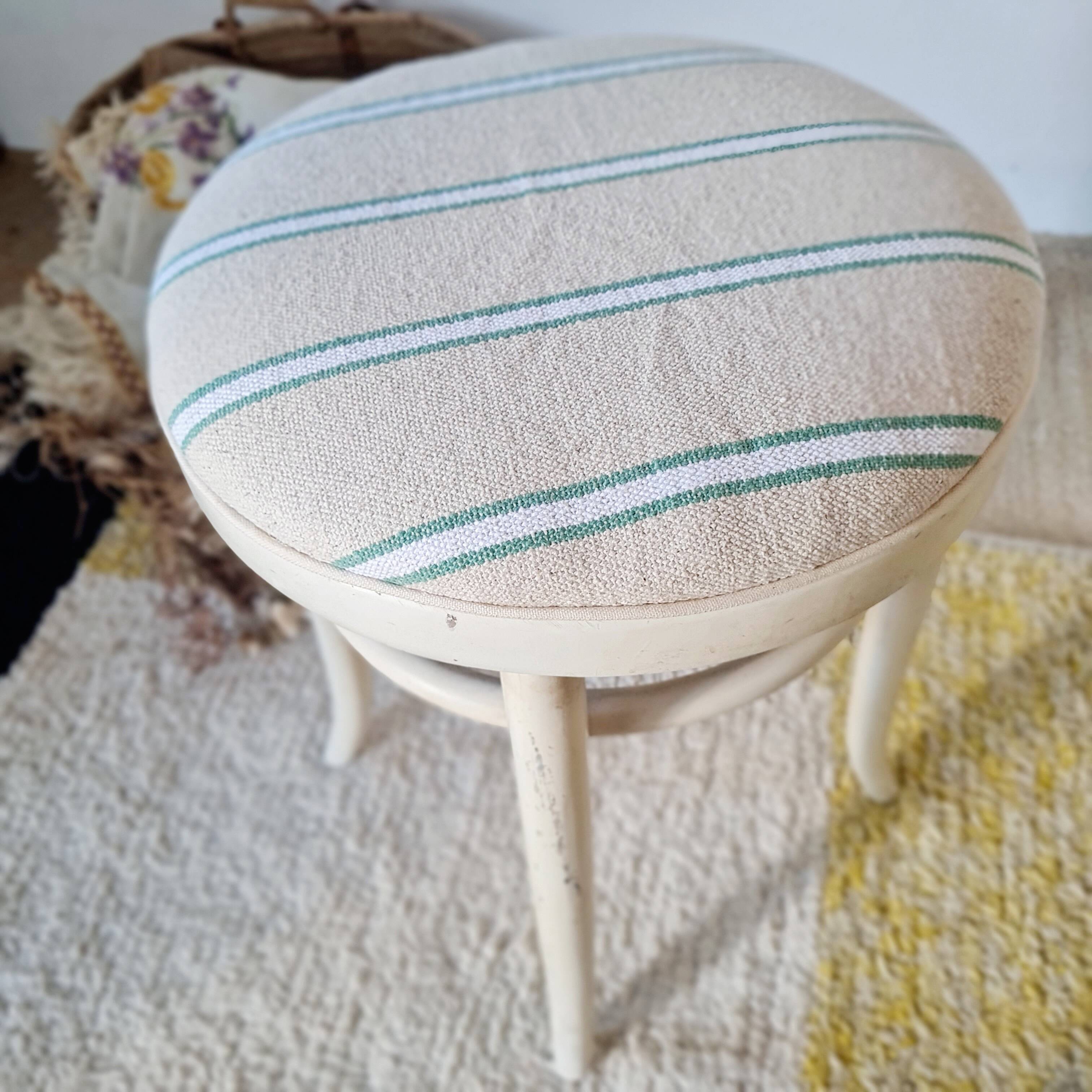 Antique stool with a wooden frame and a cream and green striped fabric seat.