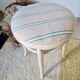 Antique stool with a wooden frame and a cream and green striped fabric seat.