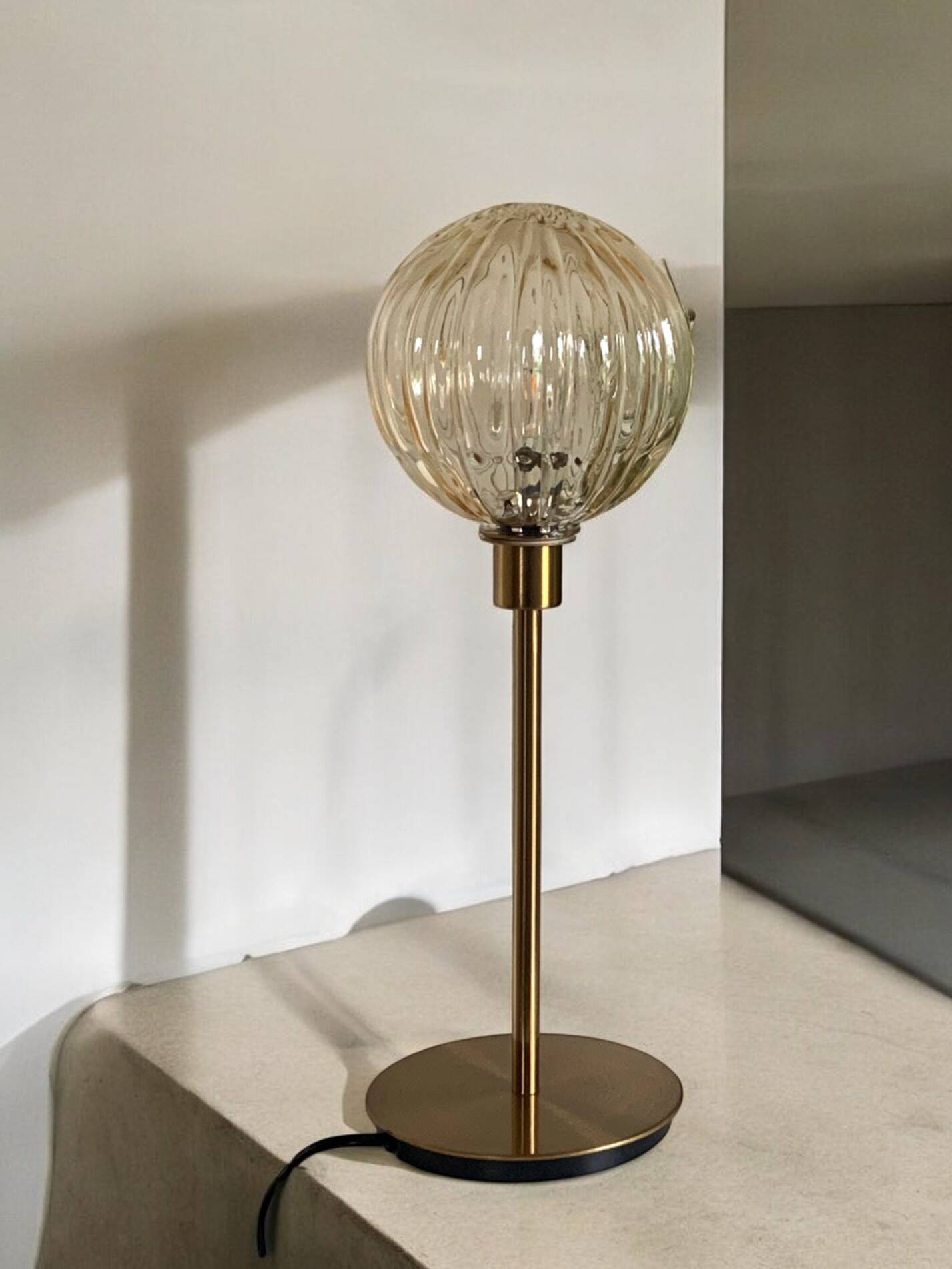Table lamp with a golden striated globe and a golden base