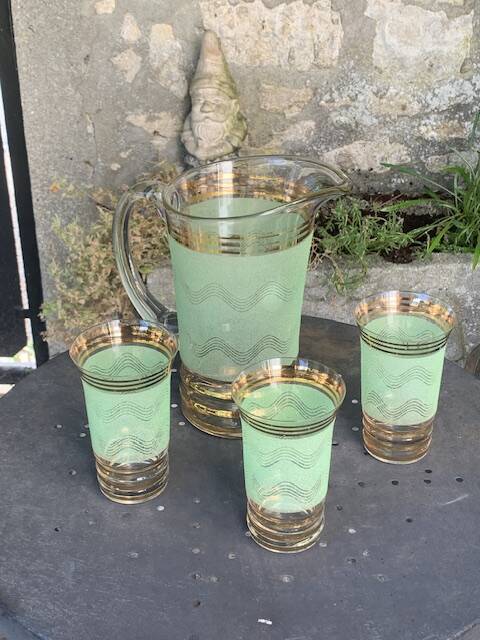 Serve an orangeade, a carafe and 3 glasses in green granite with golden trim.