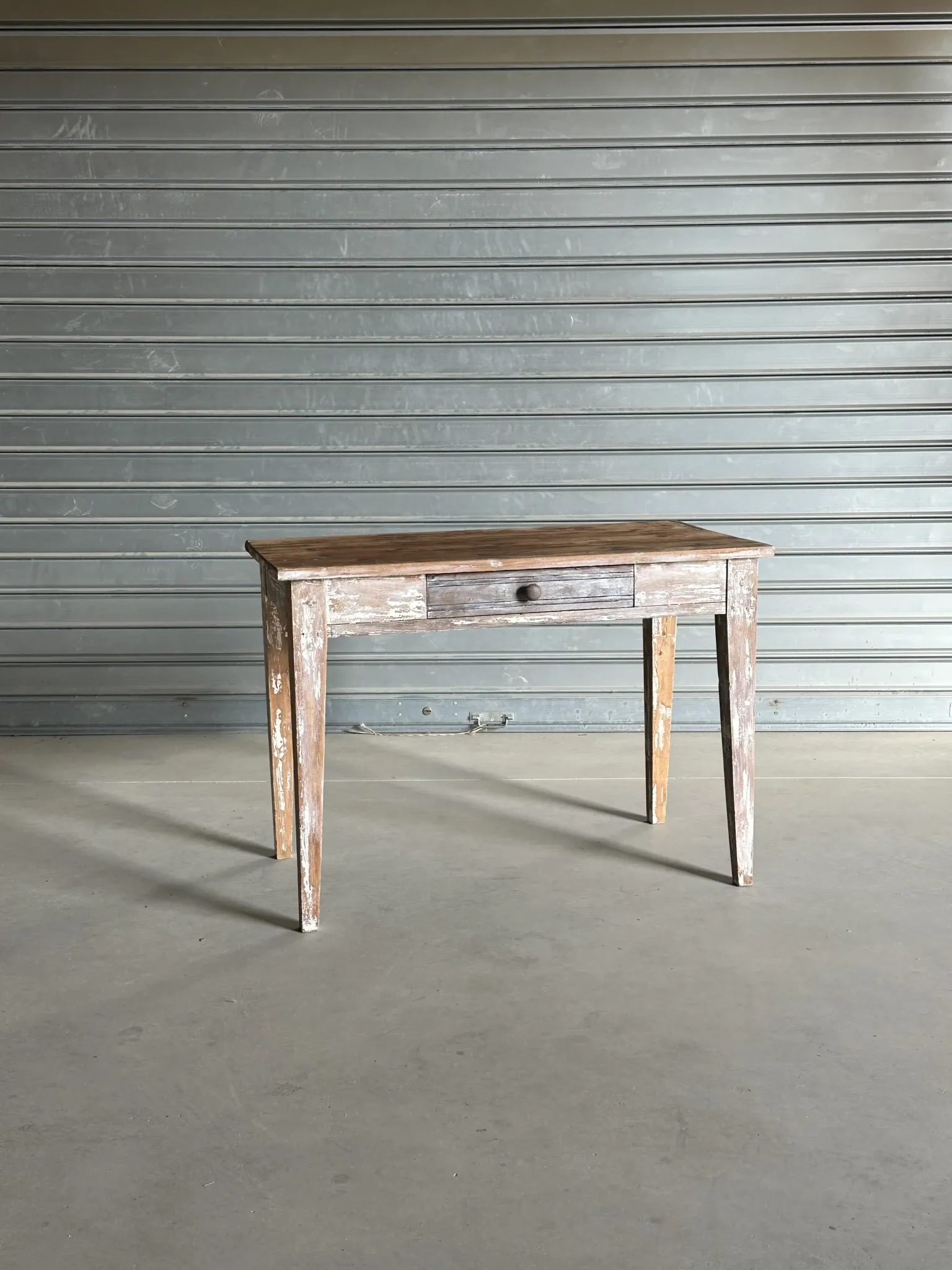 Vintage table made of raw wood with a distressed white base.
