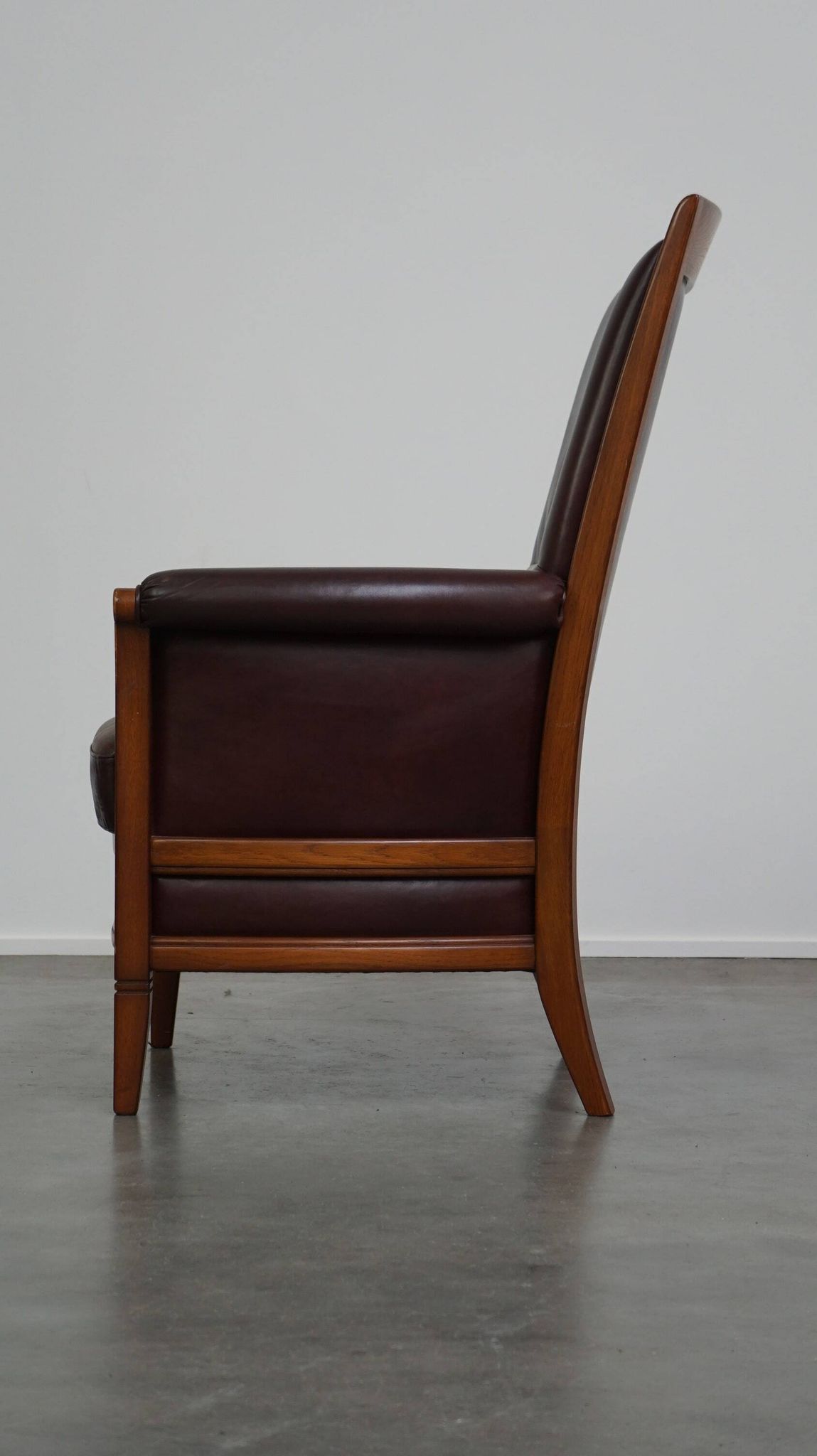 Very comfortable classic cowhide armchair with a high back in a mild Art Deco style