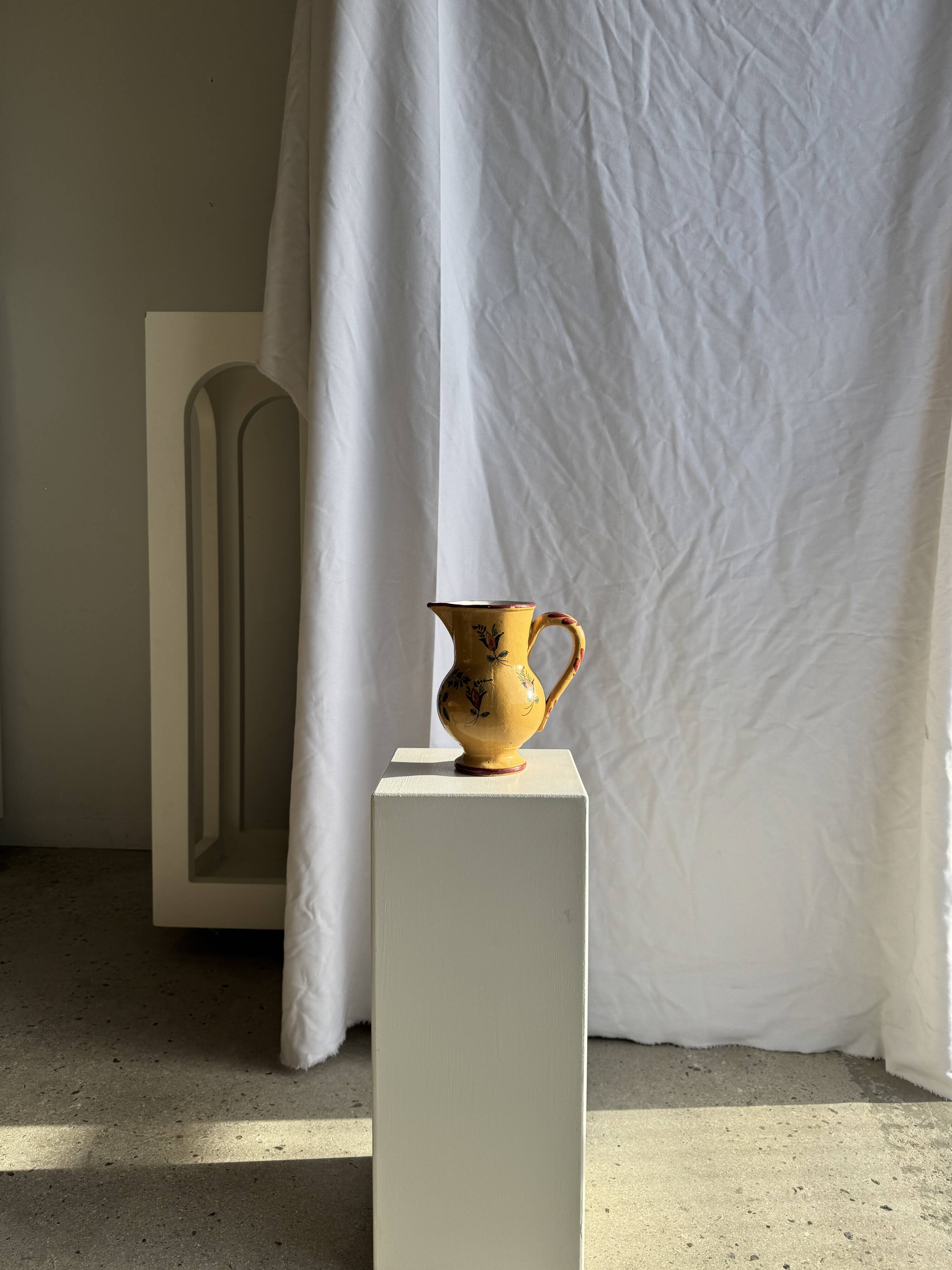 Large antique handmade ochre yellow jug with a pink flower pattern.