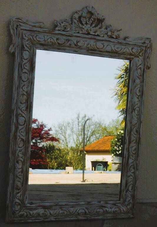 Chic and stylish antique mirror with carved wooden frame in whitewashed