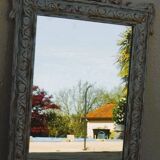 Chic and stylish antique mirror with carved wooden frame in whitewashed
