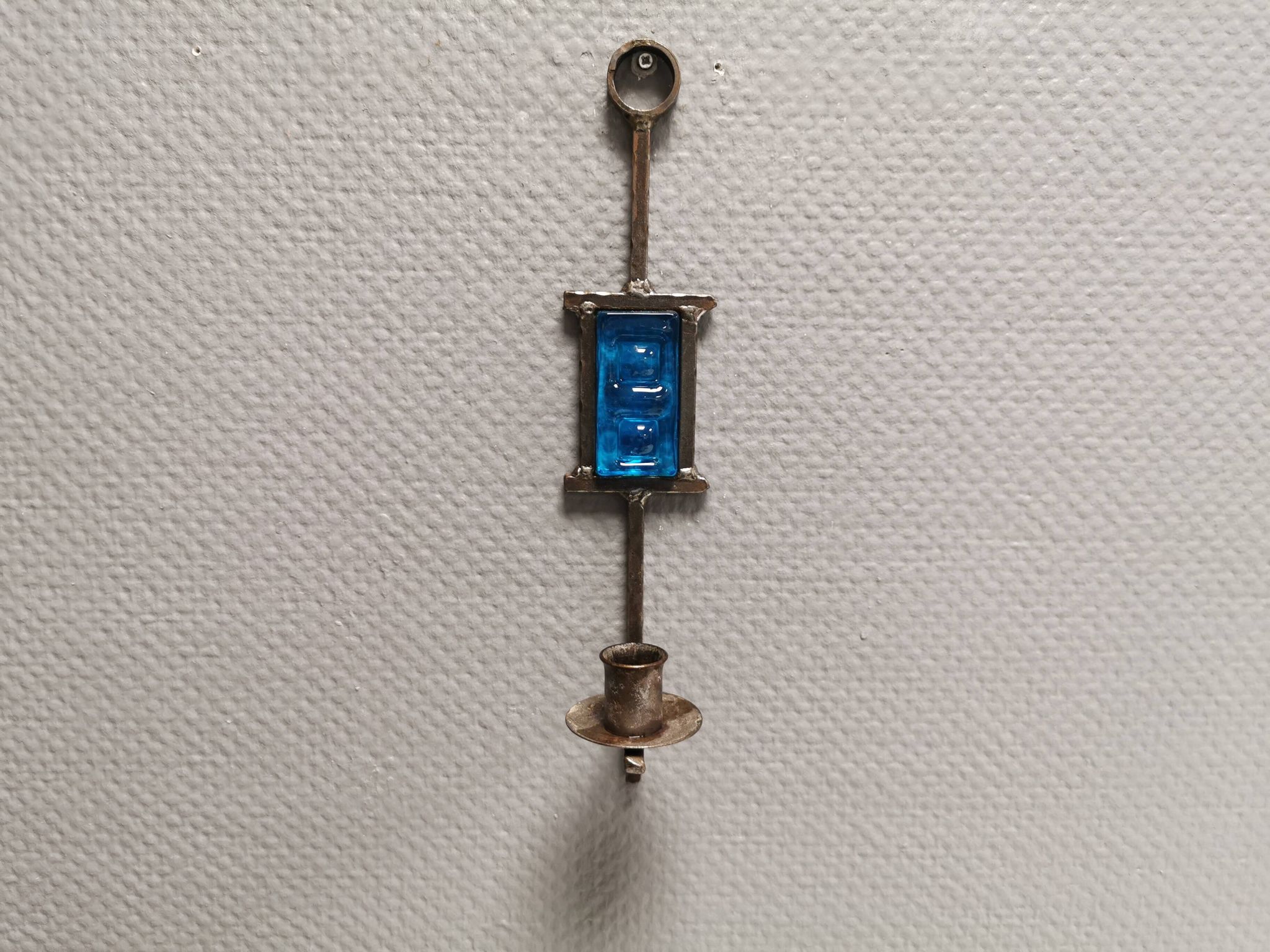 Wall-mounted candle holder in cast iron and hard pressed blue glass.