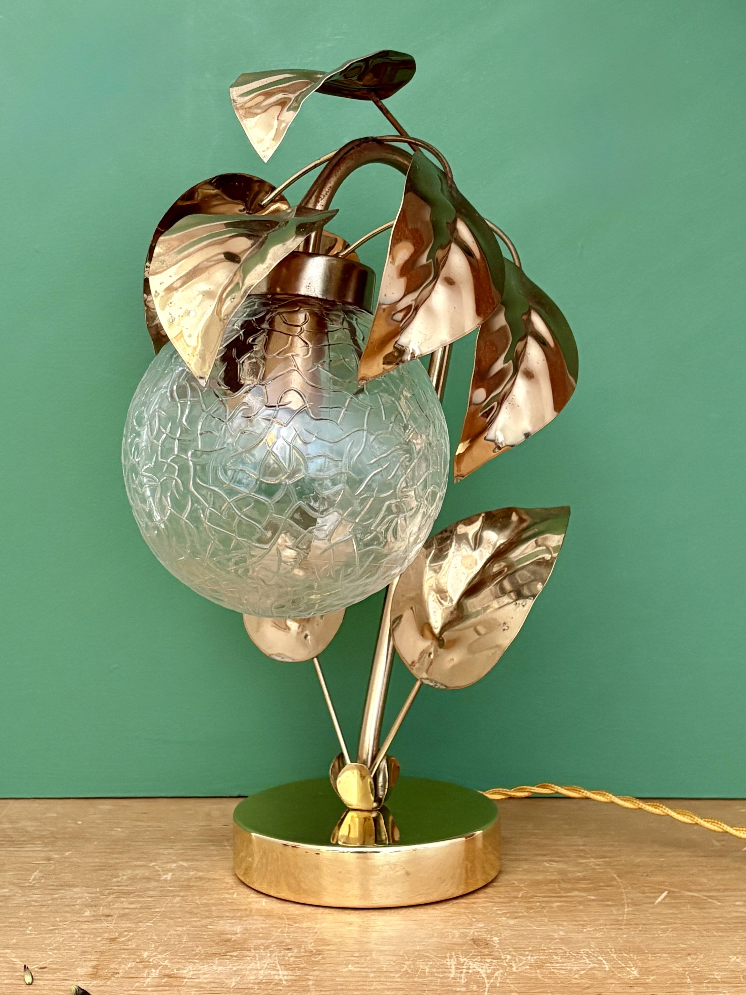 Vintage lamp with brass leaf design and transparent glass globe.