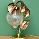 Vintage lamp with brass leaf design and transparent glass globe.