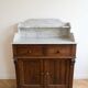Antique wooden chest of drawers with a marble top.