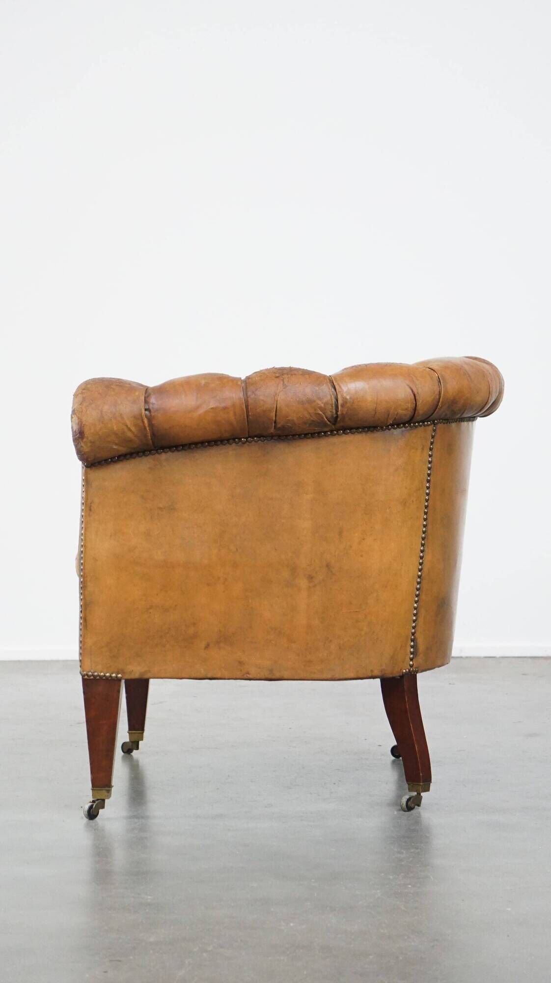 Antique, characteristic sheepskin chesterfield club chair on wheels