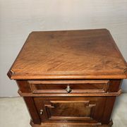 Antique wooden bedside table with turned legs.