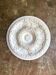 Rosette on white background, decorated with scrolls and beaded frieze ⌀ 61 cm