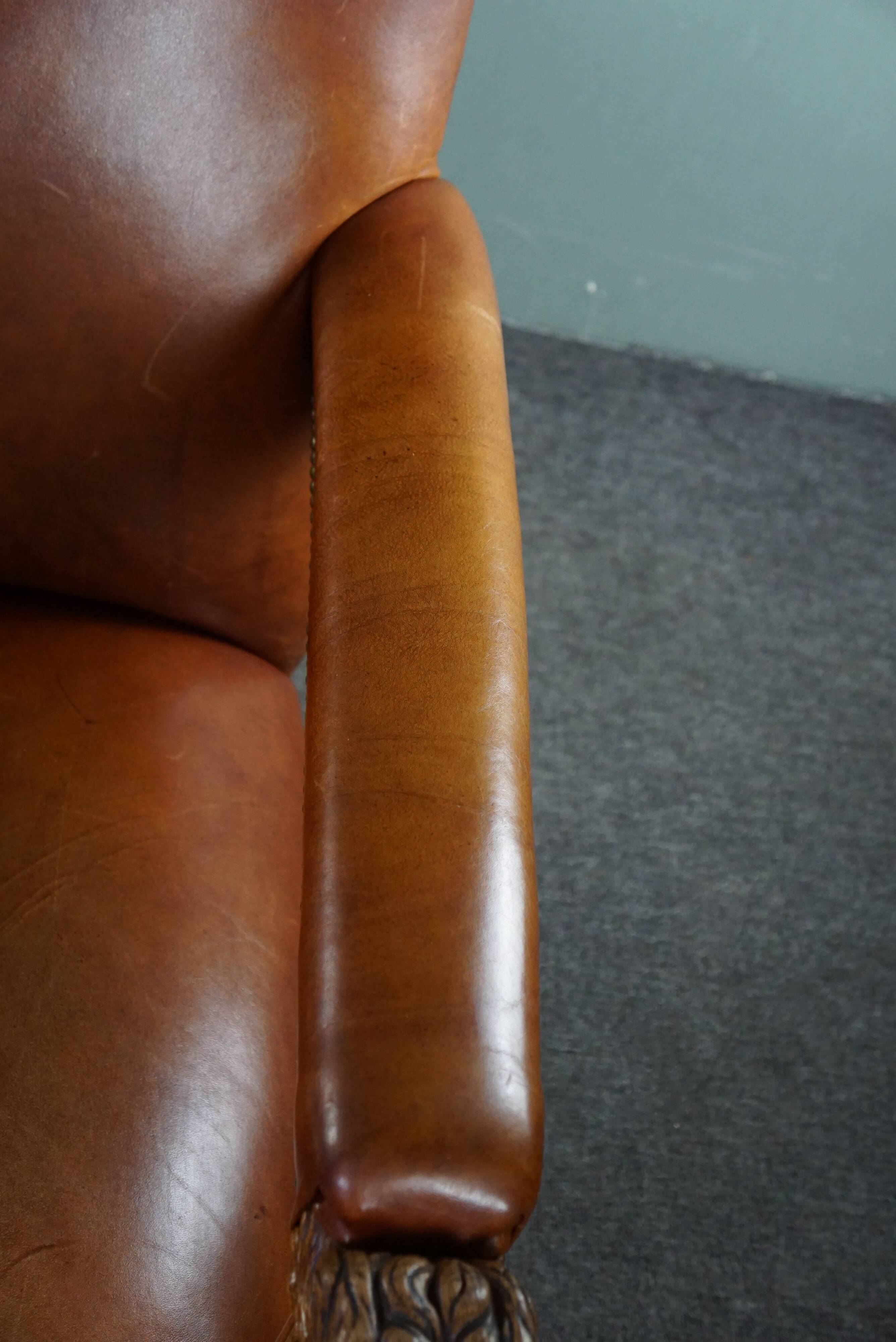 Armchair with lion heads reupholstered in cognac-colored cowhide leather