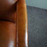 Armchair with lion heads reupholstered in cognac-colored cowhide