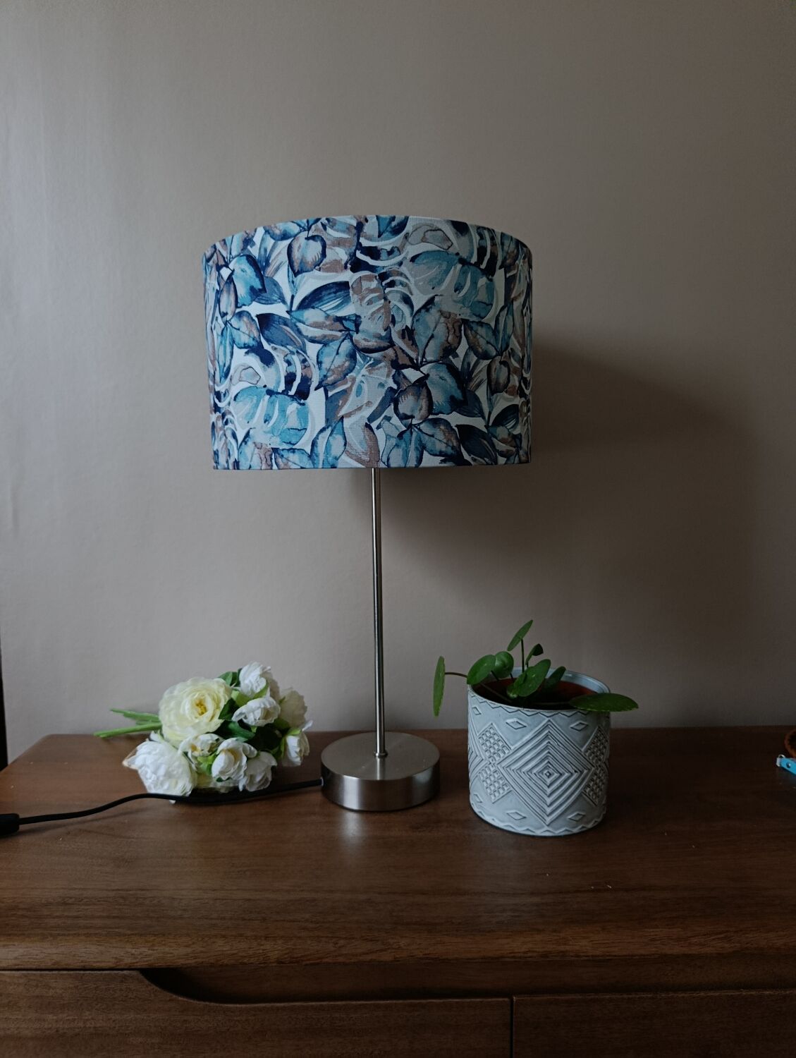 Table lamp with chrome stem, tropical plant shade.