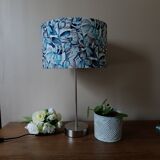 Table lamp with chrome stem, tropical plant shade.