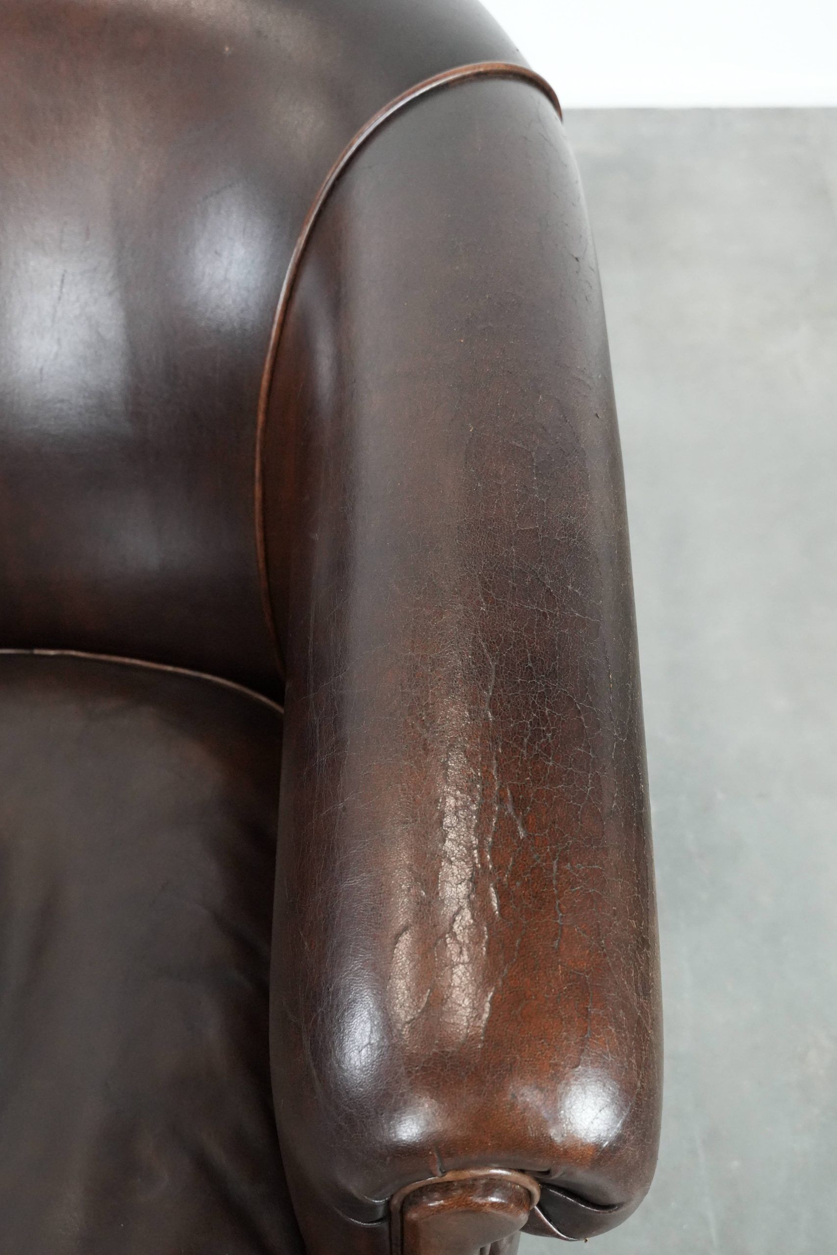 Dark brown vintage club armchair in English style made of sheepskin leather
