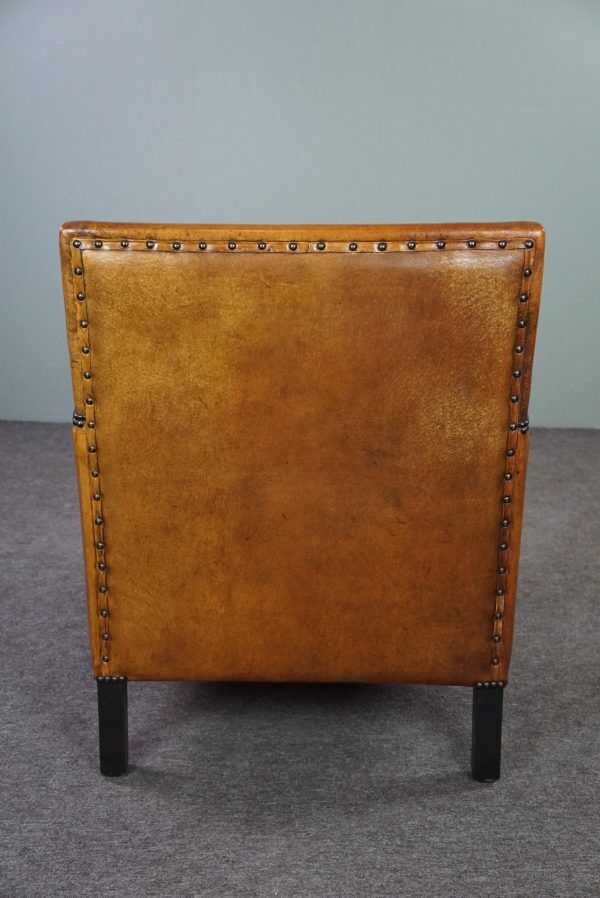 Art deco armchair in sheepskin with black piping and decorative nails