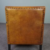 Art deco armchair in sheepskin with black piping and decorative nails