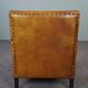 Art deco armchair in sheepskin with black piping and decorative nails