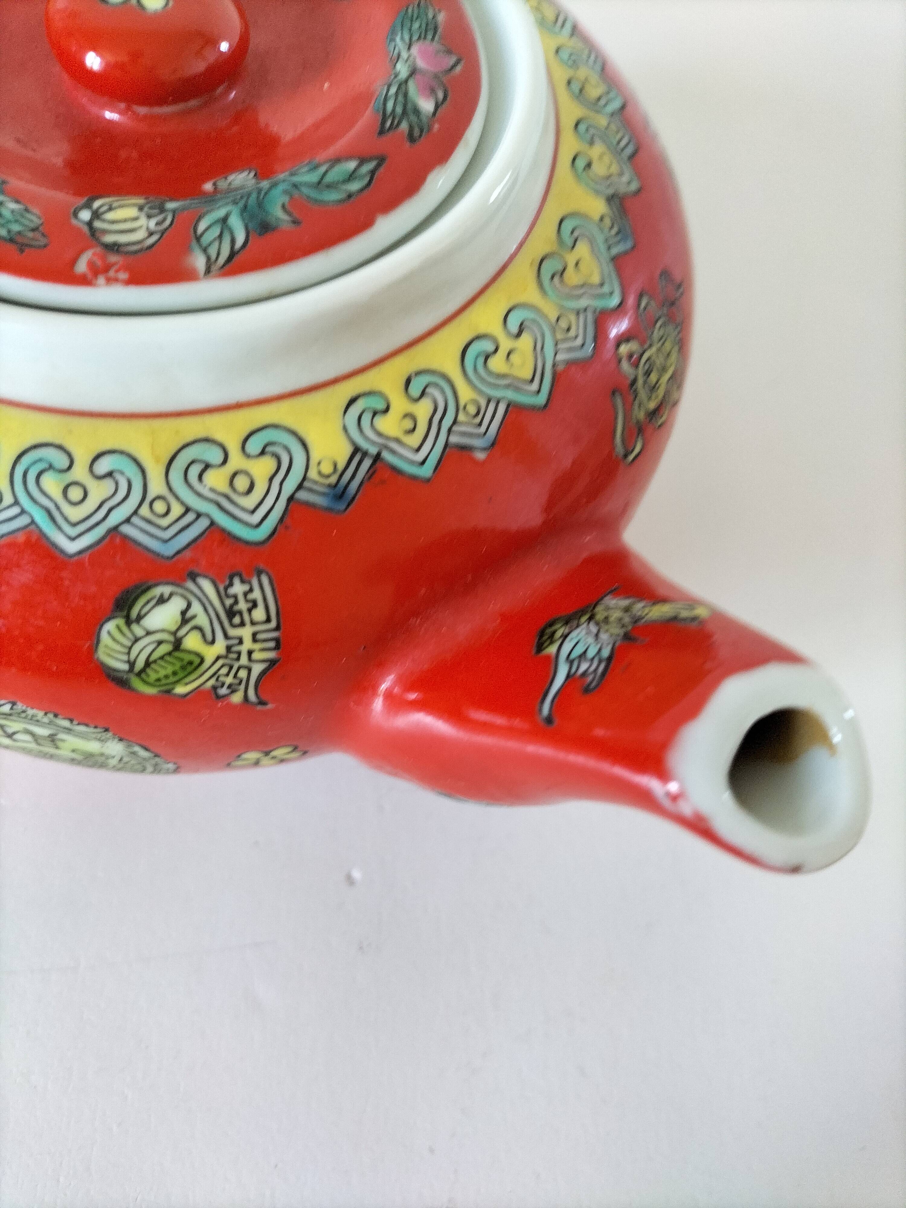 Vintage red Chinese teapot decorated with dragons and symbols.