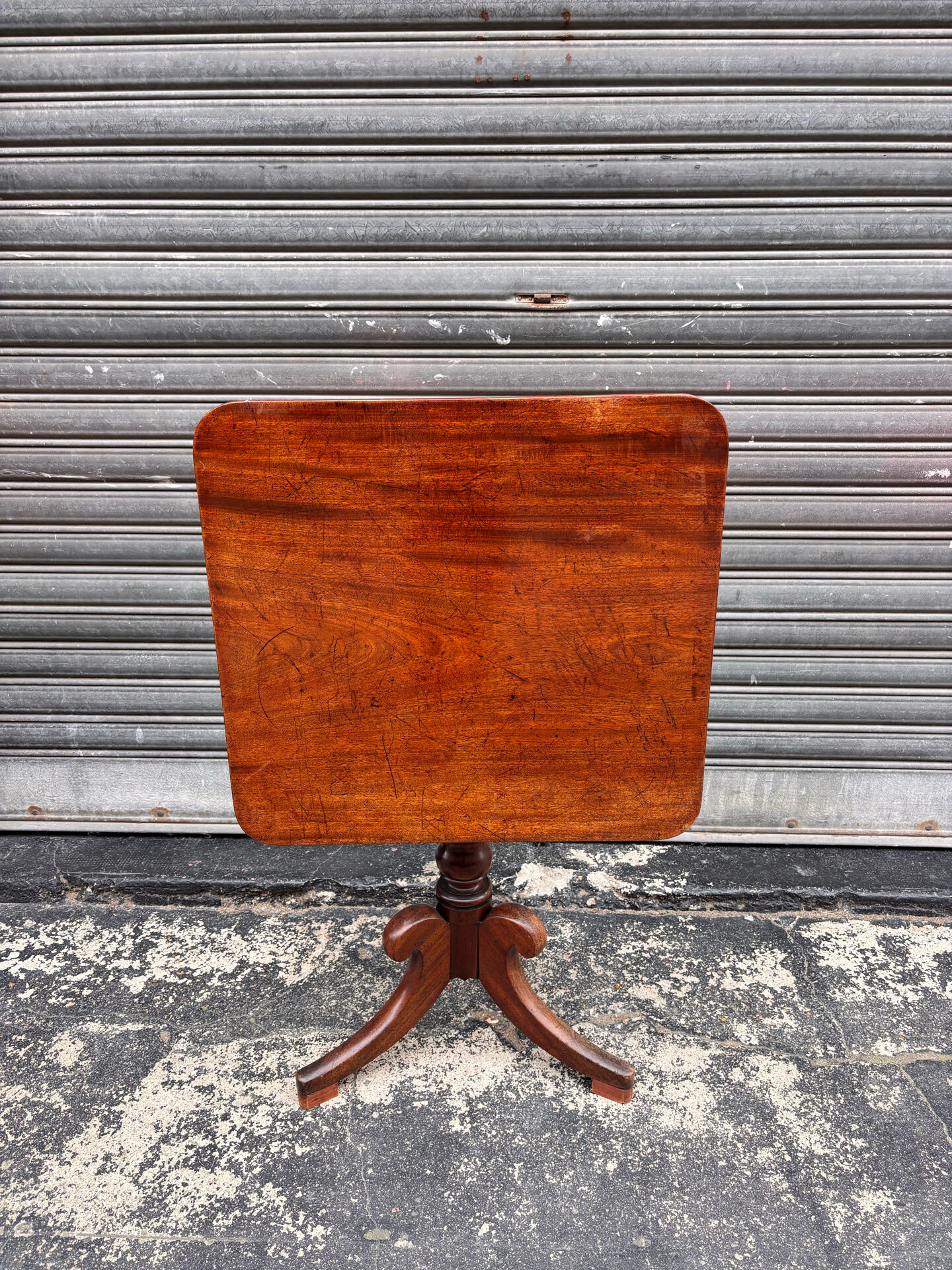 19th-century solid mahogany table with a tilting top and brass mechanism.