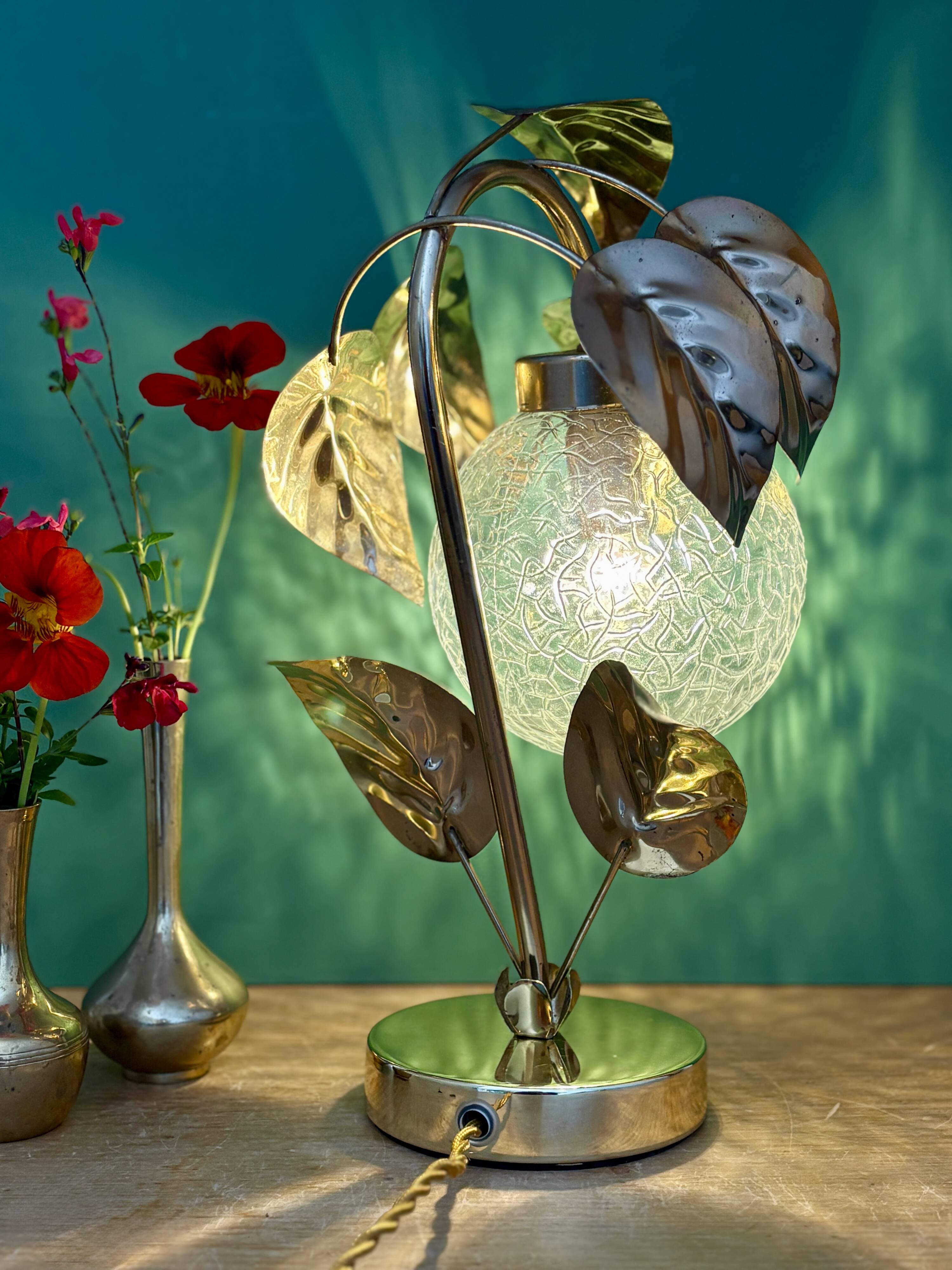 Vintage lamp with brass leaf design and transparent glass globe.