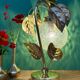 Vintage lamp with brass leaf design and transparent glass globe.