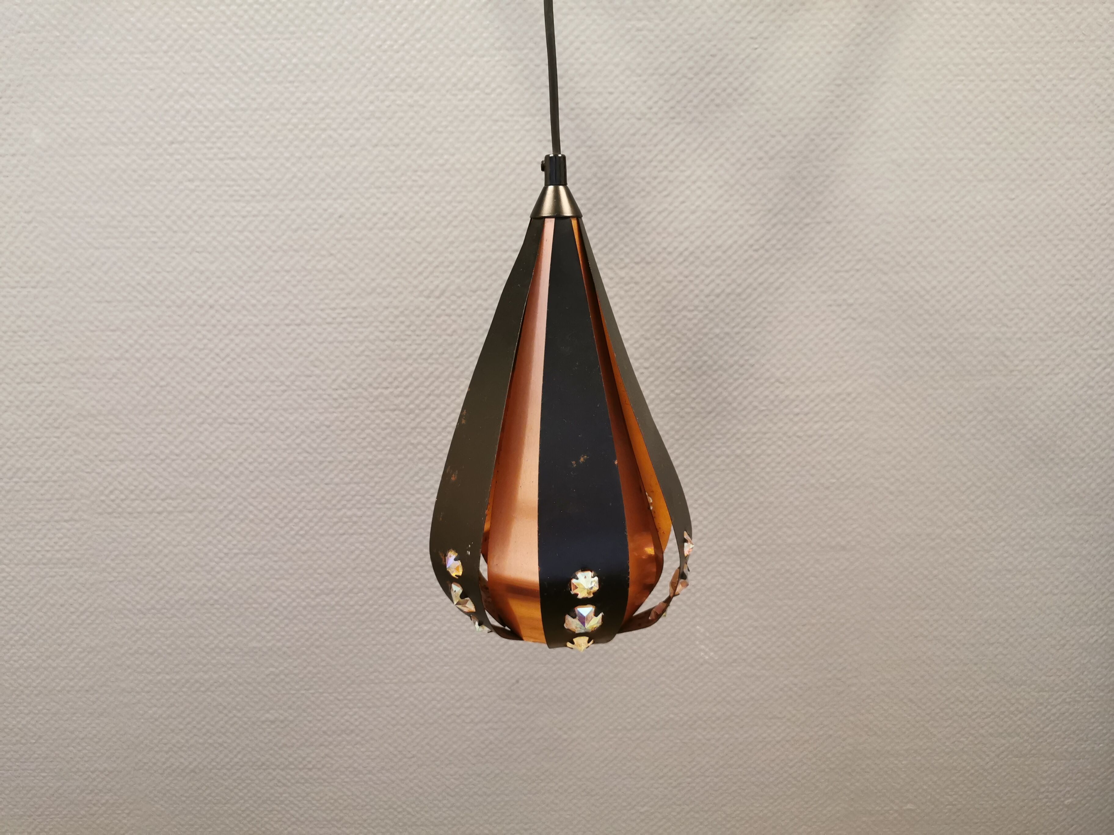 Hanging lamp in thin metal pieces, copper colored and black with prisms.