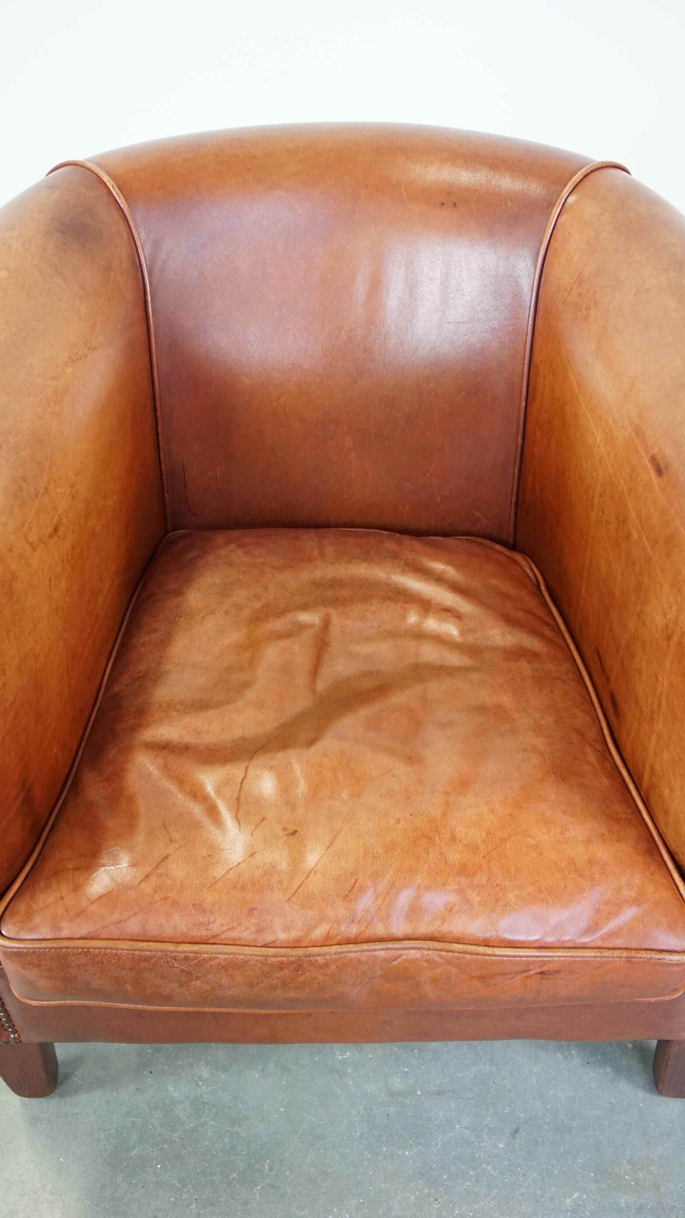 Cognac-colored cow leather club chair finished with decorative nails in English style