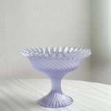 Purple glass pedestal bowl with wavy border and relief pattern.