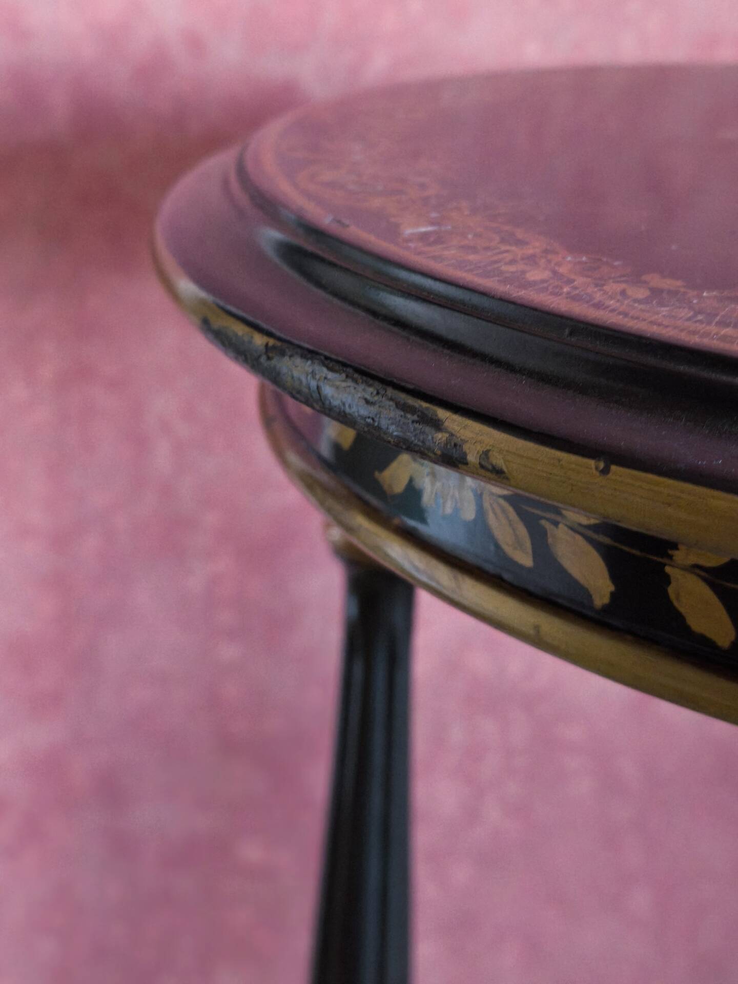 Tripod stool in blackened wood with painted floral decoration.