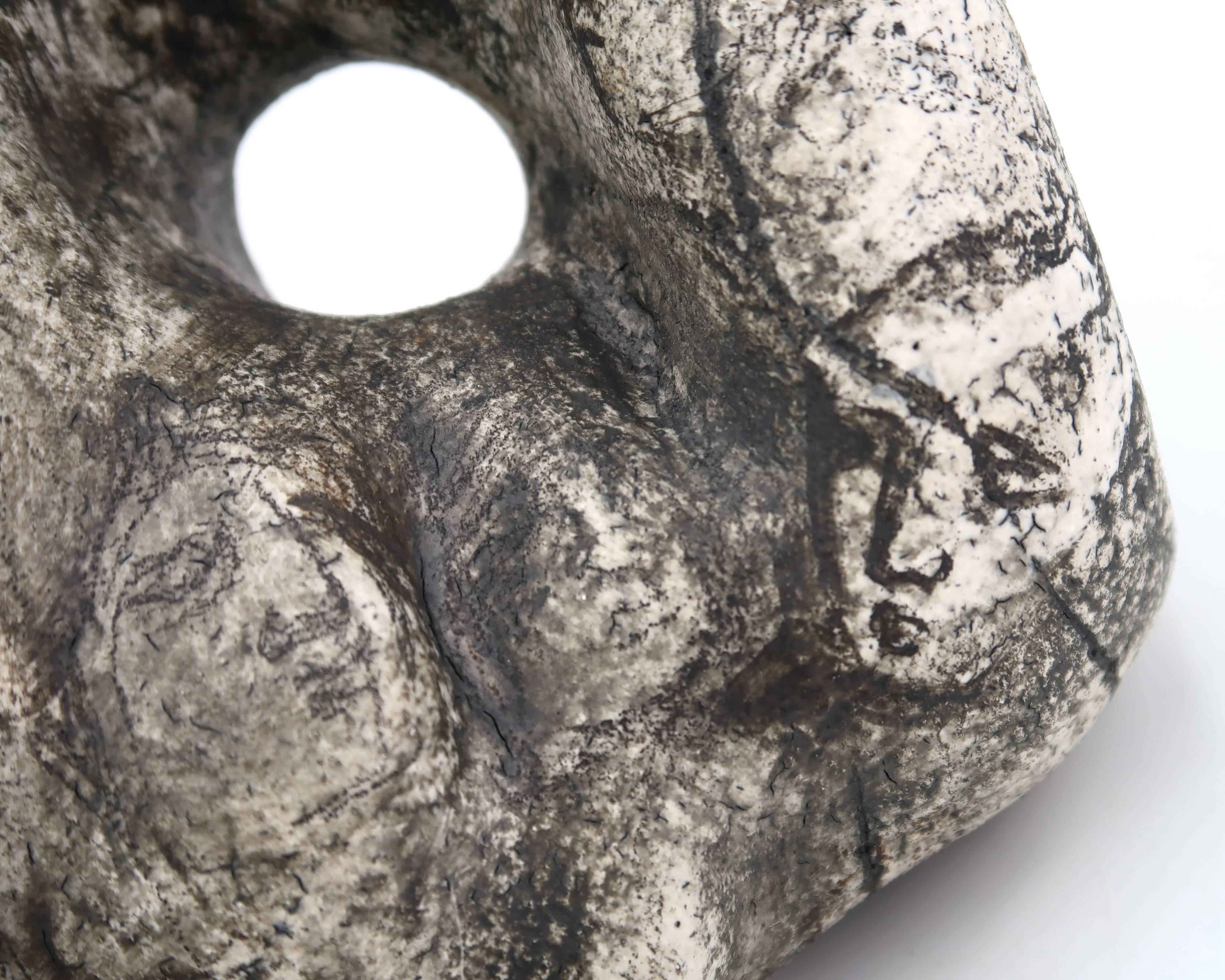 Ceramic vase sculpture decorated with faces and featuring a hole, 1980s.