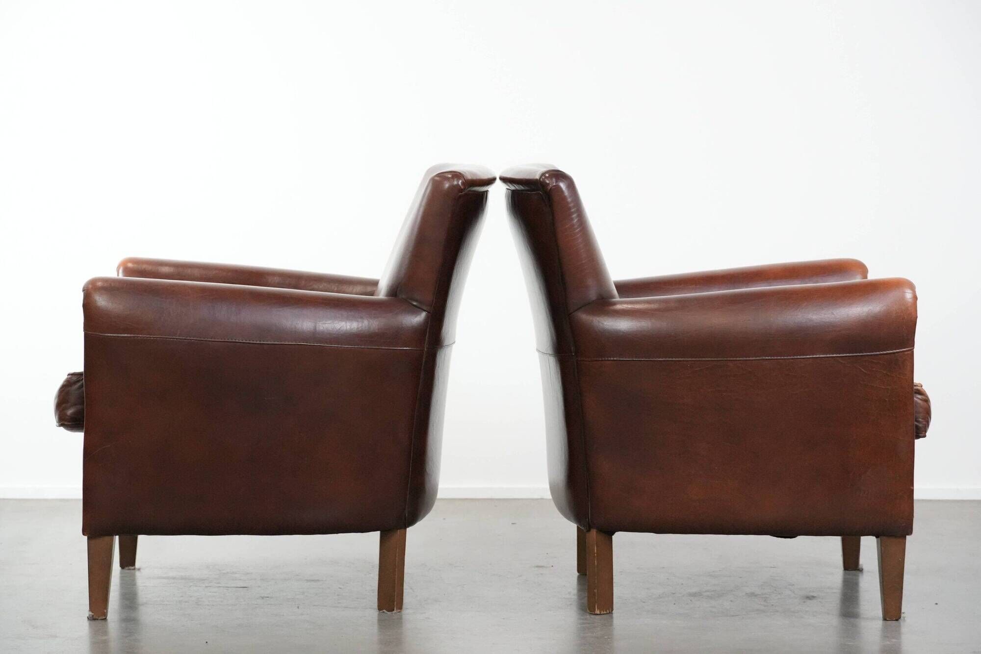 Ensemble de deux fauteuils en cuir de mouton vintage au caractère marqué.