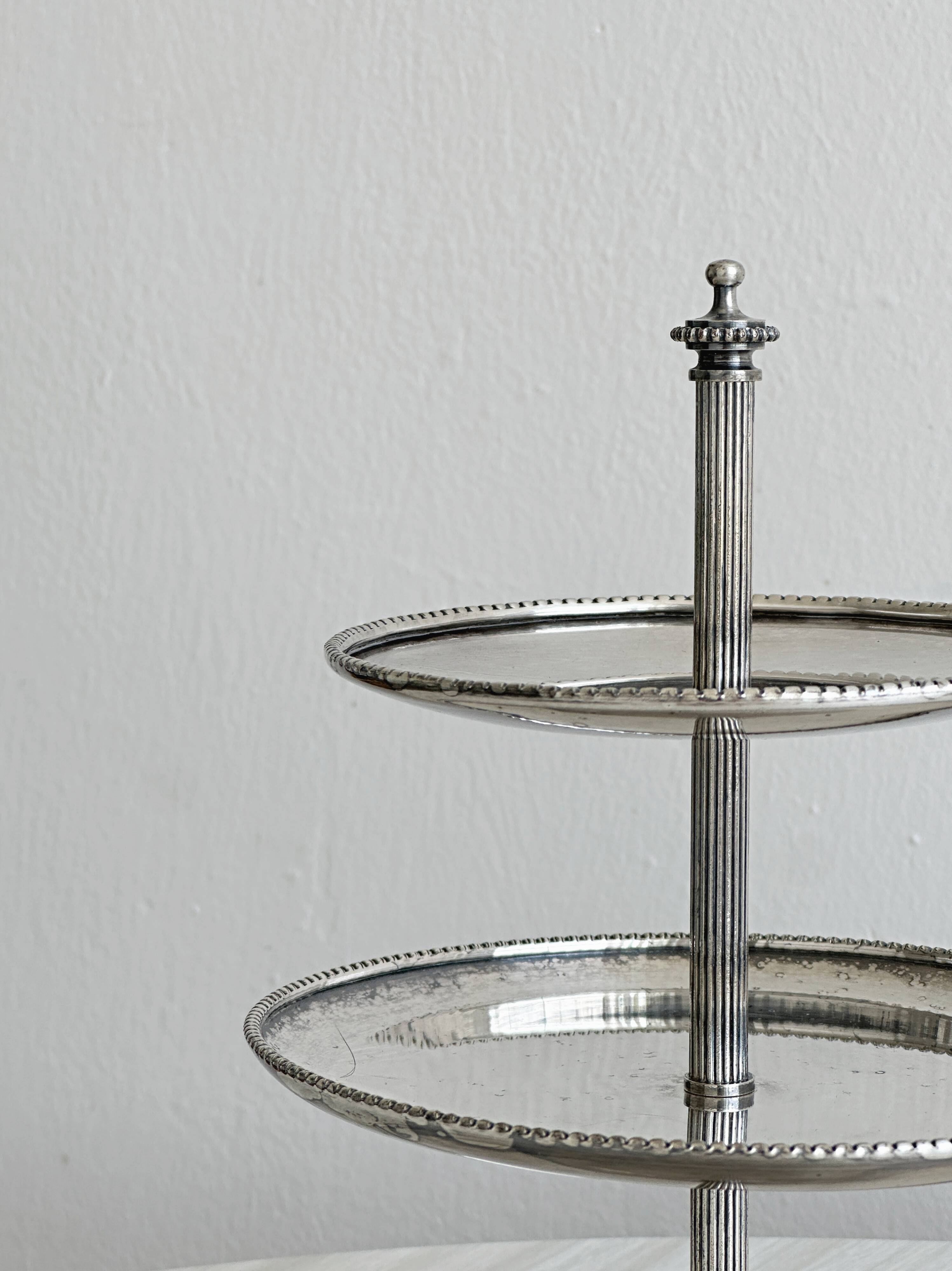 Vintage three-tiered serving stand in patinated silver metal.