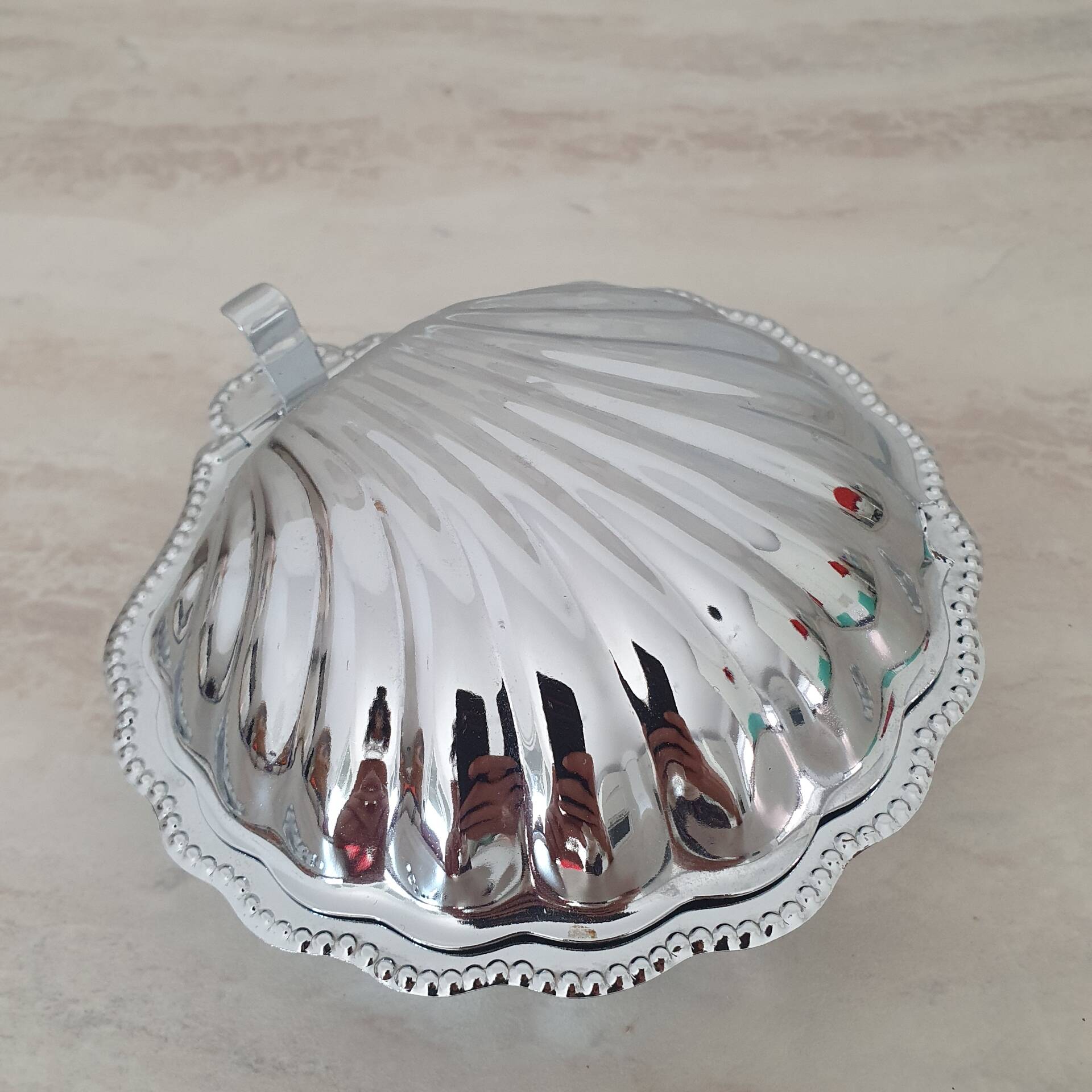 Shell-shaped butter dish in stainless steel and white glass bowl.