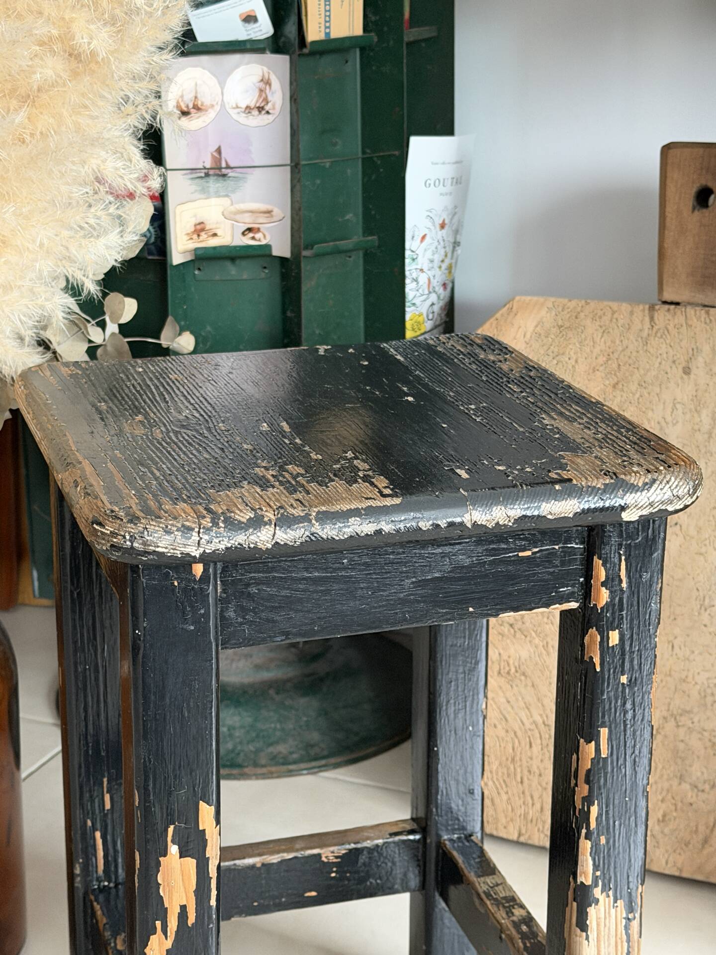 Solid wood stool with a worn black patina.