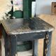 Solid wood stool with a worn black patina.