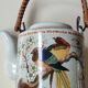 Japanese ceramic teapot. bird/paradise motifs/cherry trees. bamboo/rattan braided handle