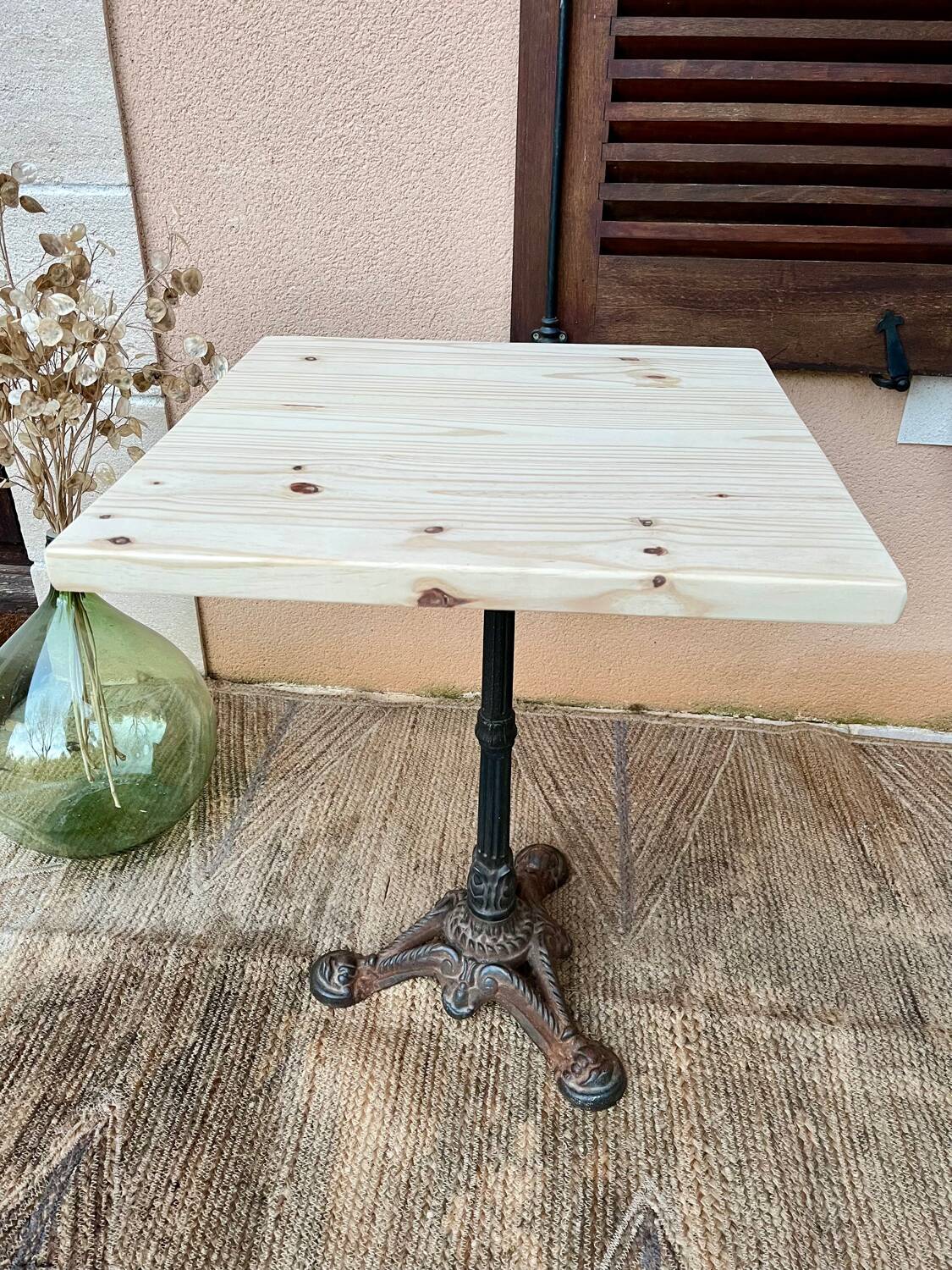Bistro table with a raw wood top and a central cast iron base.