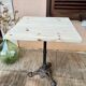 Bistro table with a raw wood top and a central cast iron base.