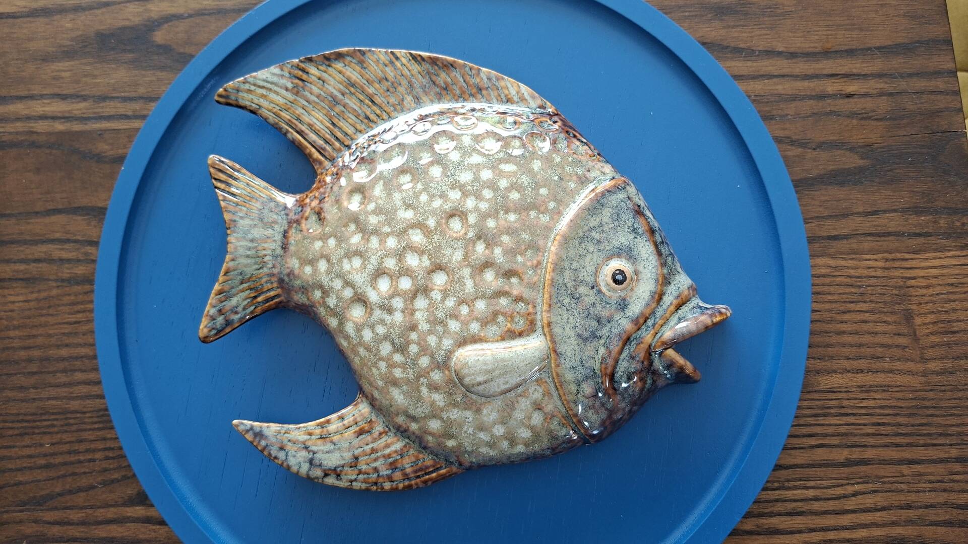 Vallauris ceramic wall sculpture of a relief fish on a blue plaque.