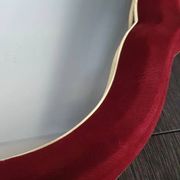 Vintage mirror with a scalloped shape in burgundy velvet and a golden trim.