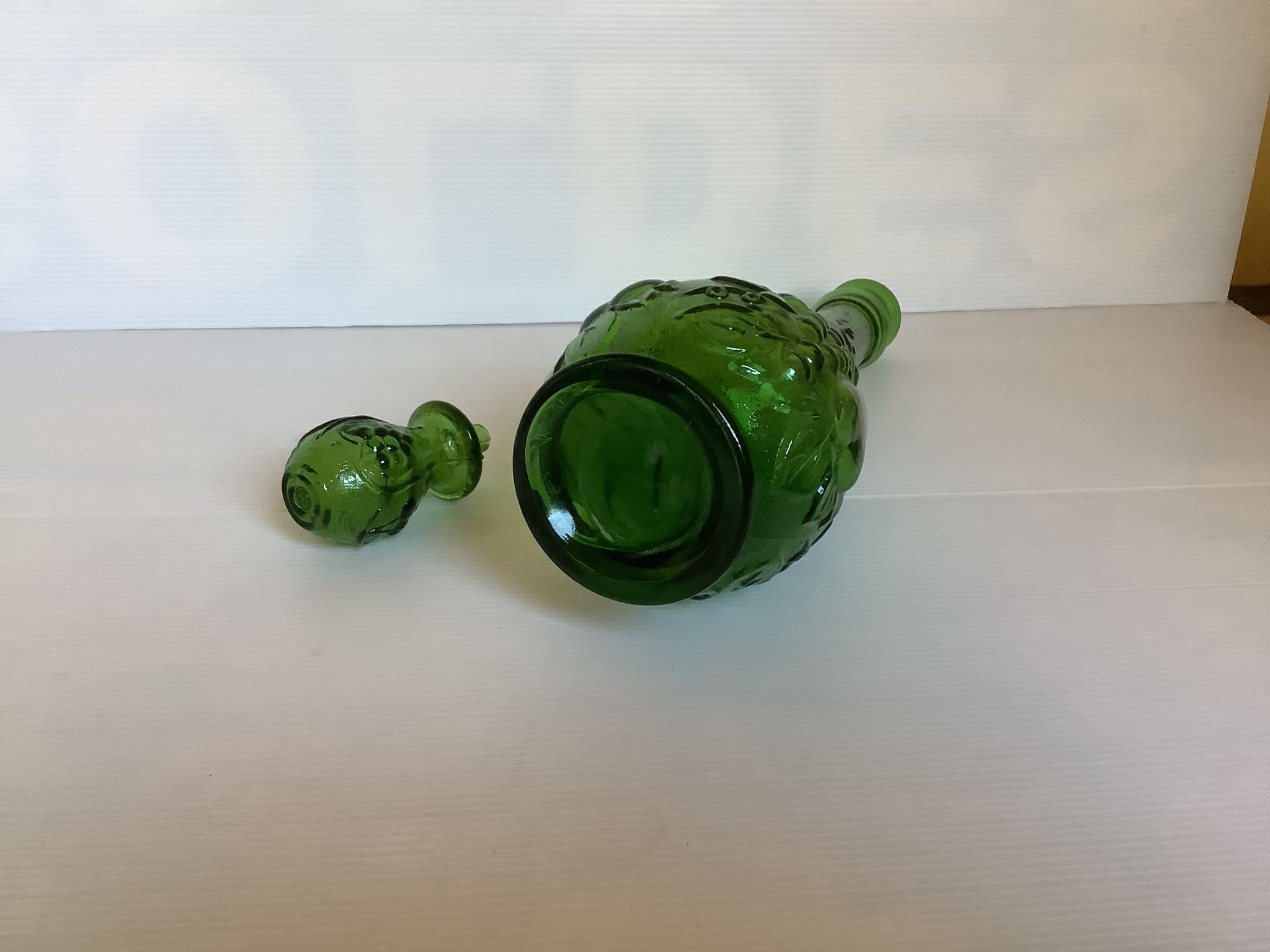 Green carafe bottle with apple, pear, and grape pattern from Italy.