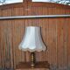 Vintage brown and gold desk lamp made of carved wood and brass, with a fringed shade.