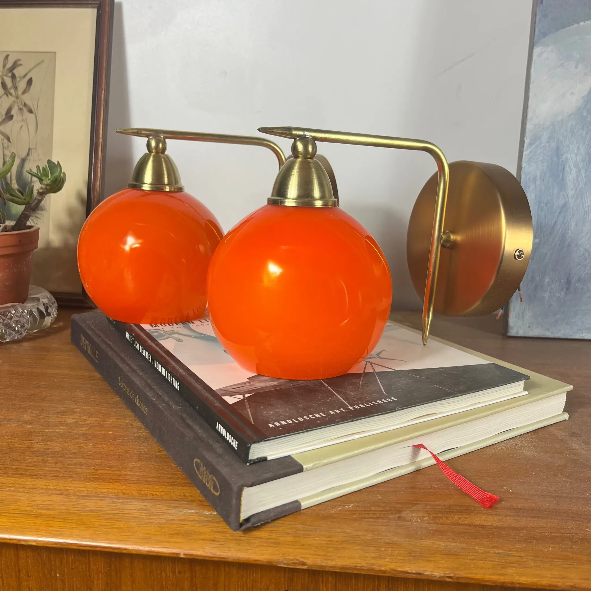 Pair of wall sconces with orange opaline glass globes and brass.
