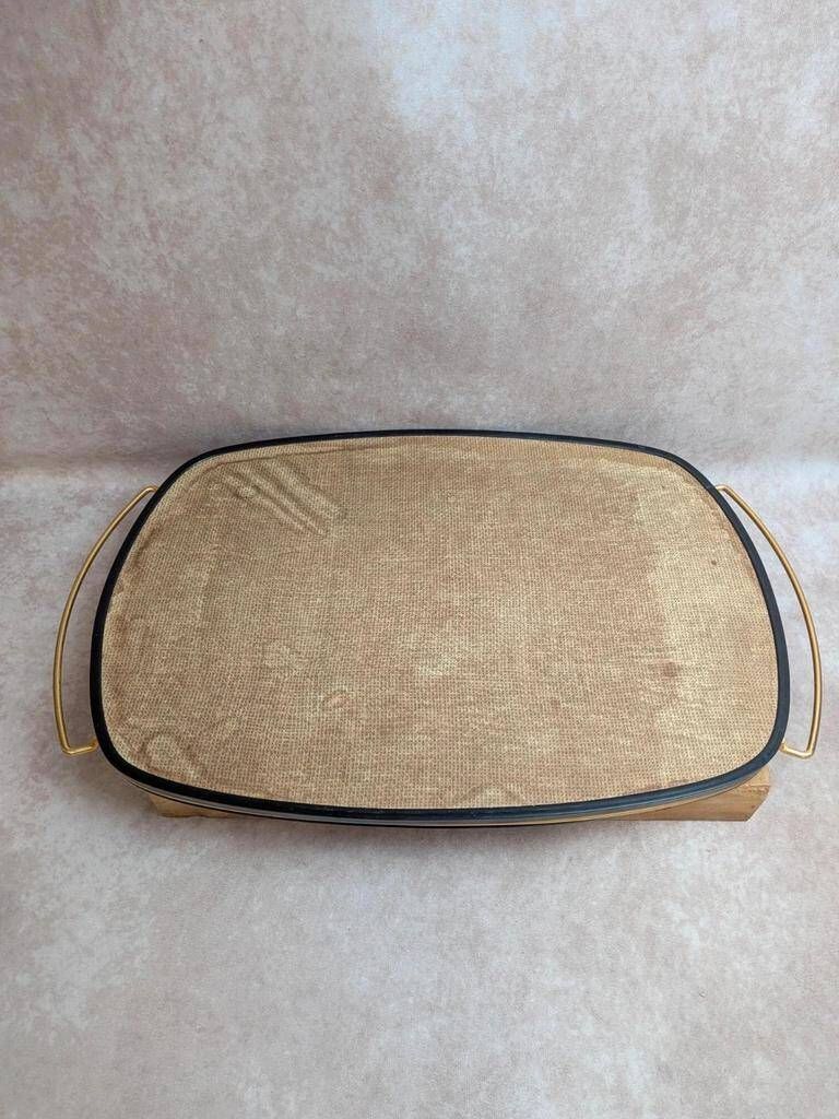 Large vintage 1960s platter with floral decoration on a black background and golden handles.