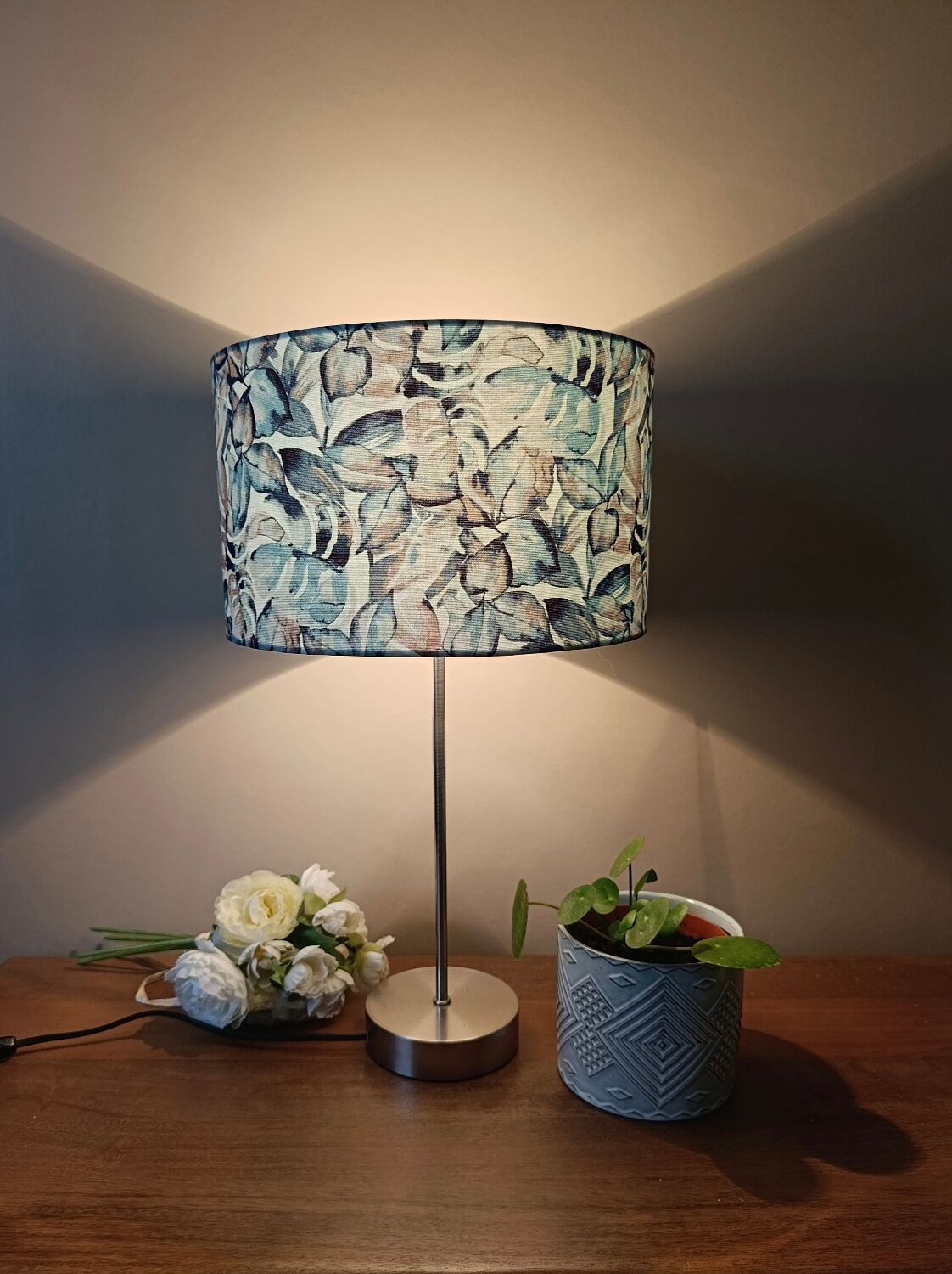 Table lamp with chrome stem, tropical plant shade.